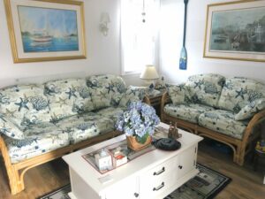 Rattan sofa & love seat with all loose pleated cushions for a seasonal cottage on Cape Cod | Upholstered in an indoor-outdoor beach theme fabric | Upholstered by Cape Cod Upholstery Shop | Located in South Dennis, MA 02660