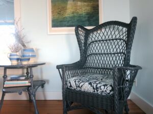 One of two matching wicker wing chairs upholstered in in a blue linen print fabric | Upholstered by Cape Cod Upholstery Shop | Located in South Dennis, MA 02660