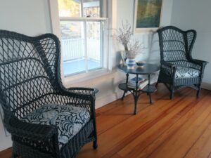 Matching wicker wing chairs upholstered in in a blue linen print fabric | Upholstered by Cape Cod Upholstery Shop | Located in South Dennis, MA 02660