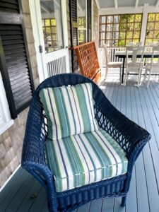 Blue Wicker chair on a covered porch | Cushion covers fabricated in a Perennials stripe indoor-outdoor fabric | Cushion inserts are rated for outdoor use | Cushions fabricated by Cape Cod Upholstery Shop | Located in South Dennis, MA 02660