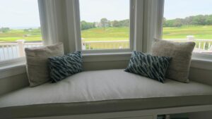 Close up view of a Large Plush 105"x32" trapezoid window seat cushion for a home with a golf course view and close to the South Cape Beach State Park | Cushion cover fabricated with Sunbrella Hybrid Smoke. Cushion Insert fabricated with a foam core wrapped in a down/feather envelope | Cushions fabricated by Cape Cod Upholstery Shop | Located in South Dennis, MA 02660