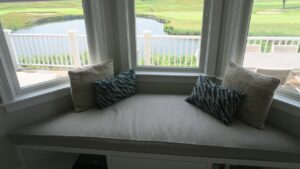 Close up view of a Large Plush 105"x32" trapezoid window seat cushion for a home with a golf course view and close to the South Cape Beach State Park | Cushion cover fabricated with Sunbrella Hybrid Smoke. Cushion Insert fabricated with a foam core wrapped in a down/feather envelope | Cushions fabricated by Cape Cod Upholstery Shop | Located in South Dennis, MA 02660