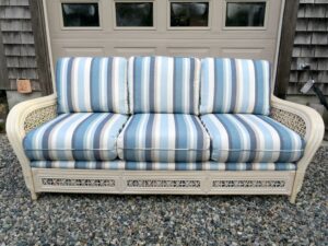 Cream Colored Rattan sofa with loose seat and back cushions | Upholstered in a Sunbrella Scope Cape stripe fabric | Upholstered by Cape Cod Upholstery Shop | Located in South Dennis, MA 02660