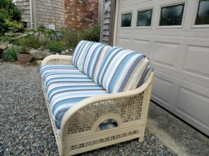 Cream Colored Rattan sofa with loose seat and back cushions | Upholstered in a Sunbrella Scope Cape stripe fabric | Upholstered by Cape Cod Upholstery Shop | Located in South Dennis, MA 02660