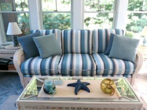 Rattan sofa shown in the clients three season room. Upholstered in a Sunbrella Scope Cape stripe fabric | Upholstered by Cape Cod Upholstery Shop | Located in South Dennis, MA 02660