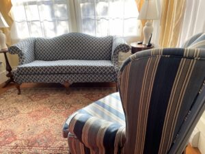 Camel Back sofa and wing chair in a 1850's Cape Cod home. Camel Back sofa upholstered in a navy blue diamond pattern fabric. Wing chair upholstered in a rayon stripe. Cape Cod Upholstery Shop | Located in South Dennis, MA 02660